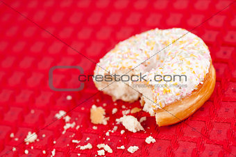 Half eaten doughnut on a red tablecloth