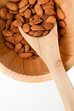 Wooden spoon with almonds in in a bowl
