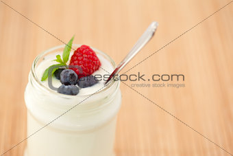 Close up of a pot yogurt with leaves red berries