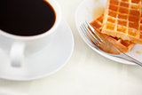 Waffles placed next to a coffee cup