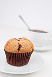 Muffin and a cup of coffee with a spoon on white plates