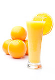 Pile of oranges behind a glass of orange juice