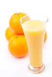 Oranges behind a glass of orange juice