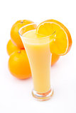 Full glass of orange juice placed near a heap of oranges