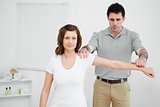 Serious osteopath pressing down the arm of a patient