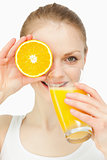 Woman placing an orange on her eye while drinking in a glass