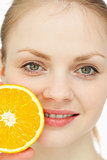 Close up of a woman placing an orange on her lips
