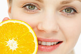 Close up of a woman placing an orange near her lips