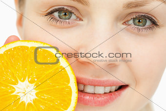 Close up of a woman placing an orange near her lips