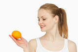 Woman holding a tangerine while looking at it