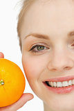 Close up of a cheerful woman holding an orange