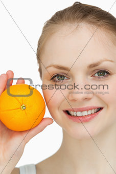 Fair-haired woman presenting an orange