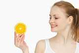 Woman presenting an orange slice while looking at it