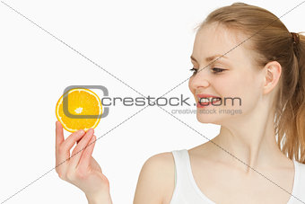 Woman presenting an orange slice while looking at it