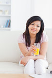 Woman sitting on a sofa while holding a glass of orange juice