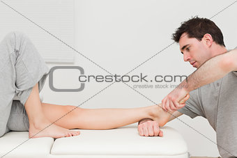 Serious doctor stretching the foot of his patient