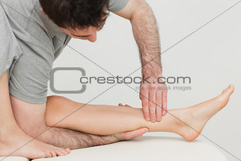 Serious osteopath massaging the shin bone of a patient