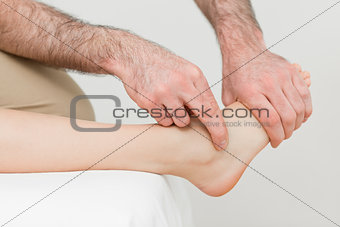 Hands of a physiotherapist massaging the foot of a patient