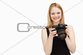 Woman holding a SLR camera while smiling