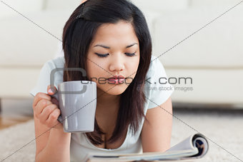 Woman holding a mug while reading a magazine