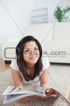 Woman lies on the floor and holds a magazine