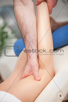Doctor extending the leg of his patient while holding his ankle 