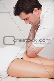 Chiropractor massaging the thigh of his patient while using his 