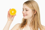 Joyful woman presenting an orange while looking at it