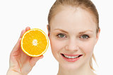 Close up of a smiling woman presenting an orange