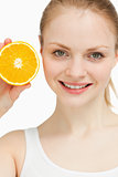 Close up of a joyful woman presenting an orange