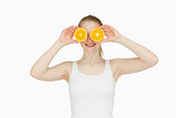 Blond-haired woman placing oranges on her eyes