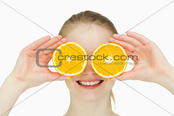Close up of a smiling woman placing oranges on her eyes