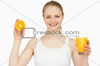 Woman holding a glass while presenting an orange