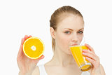 Woman presenting an orange while drinking