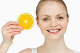 Cheerful woman holding a slice of orange