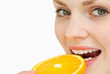 Close up of a woman placing a slice of an orange in her mouth