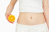 Woman placing an orange next to her belly