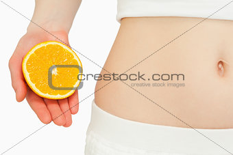 Woman placing an orange near her belly