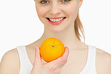 Close up of a woman holding an orange while smiling