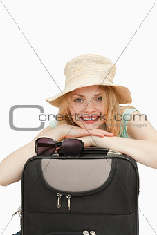 Smiling woman leaning on a suitcase