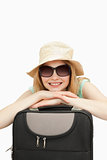 Close up of a smiling woman leaning on a suitcase