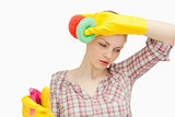 Young woman wiping her forehead while holding sponges