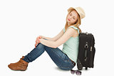 Tired woman sitting against a suitcase