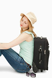 Blonde-haired woman sitting against a suitcase