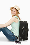 Smiling woman sitting against a suitcase