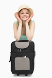 Smiling woman leaning on a suitcase while sitting