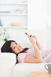 Woman resting on a couch while holding a phone