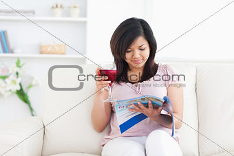 Woman holding a glass of red wine while reading a magazine