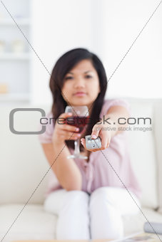 Blurred woman holding a glass of red wine and a television remot