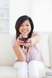 Woman drinking a glass of wine while holding a television remote